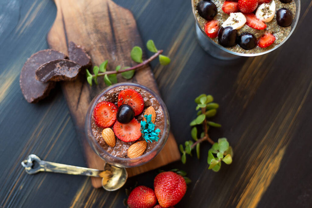 Chocoladepudding met chia, chocolade en aardbeien op een blauwe tafel - Foto, afbeelding