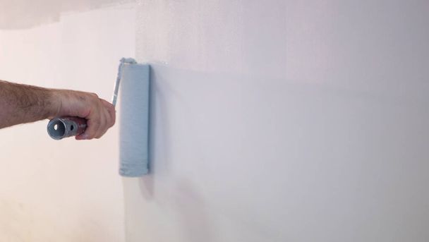 Decorators hand schilderen muur met roller. - Foto, afbeelding