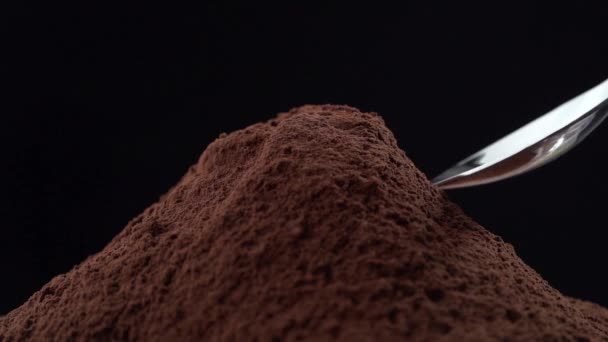 Zeitlupe der Kakaopulver-Dosierung mit einem kleinen Löffel auf schwarzem Hintergrund - Filmmaterial, Video
