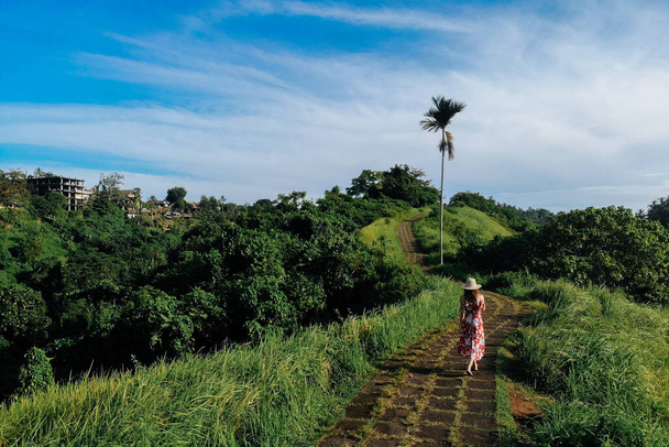 Young beautiful woman walking on Campuhan Ridge way of artists, in Bali, Ubud. Beautiful calm sunny morning. - Photo, Image