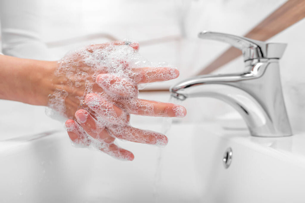 Alguien se lava las manos con jabón mientras está de pie en el baño
. - Foto, imagen
