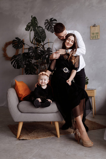 Portrait of beautiful young parents and their cute little daughter hugs, smiling indoors. mother's, father's, baby's day. concept of family. family look. - Photo, image