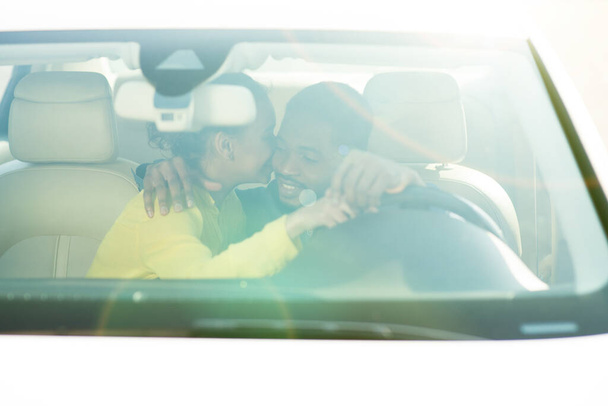 Африканская женщина целует мужчину в машине, празднуя покупку нового автомобиля
 - Фото, изображение