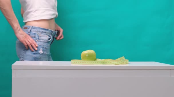 Női karcsúsított gyomor és zöld alma az előtérben, szelektív fókusz. A fogyás és a megfelelő táplálkozás fogalma - Felvétel, videó