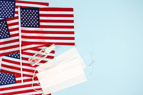 Flat lay composition with american flags, disposable protective masks and sanitizer on blue background with copyspace for text. National symbol, Independence Day celebration and healthcare concept - Photo, image
