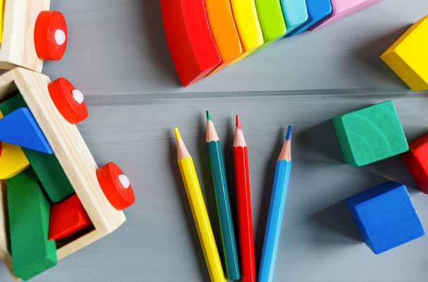 Close up Cubi di legno multicolore con lettere, matite, arco arcobaleno su sfondo grigio. Set di giocattoli per studiare alfabeto. Educazione, ritorno al concetto di scuola. Vista dall'alto, copia spazio - Foto, immagini
