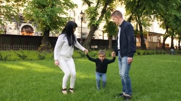 Mutter und Vater amüsieren sich mit dem Sohn auf dem Rasen - Filmmaterial, Video