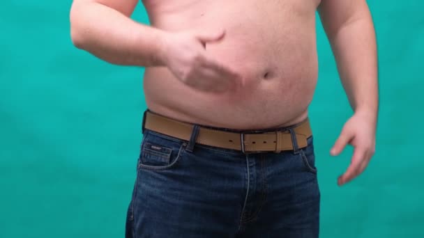 L'uomo grasso con la pancia grande mostra un segno con la mano. Il concetto di mangiare sano e perdere peso, dieta
. - Filmati, video