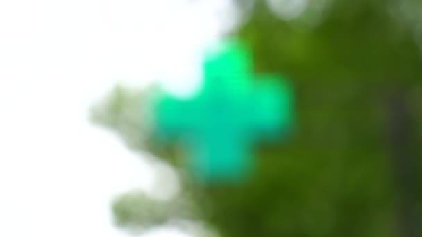 πράσινο σημάδι του φαρμακείου σταυρό με θαμπάδα στο φόντο του πράσινου ξύλου. Πολύ υψηλής ποιότητας υλικό - Πλάνα, βίντεο