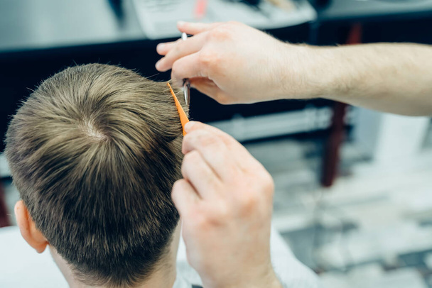 Татуед Барбер підстригає волосся клієнта ножицями. Закрийся. У перукарні привабливий самець підстригається. Вигляд зблизька. - Фото, зображення