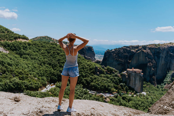 a girl stands on a cliff of Meteora - Greece - and looks at the valley. summer vacation - Valokuva, kuva