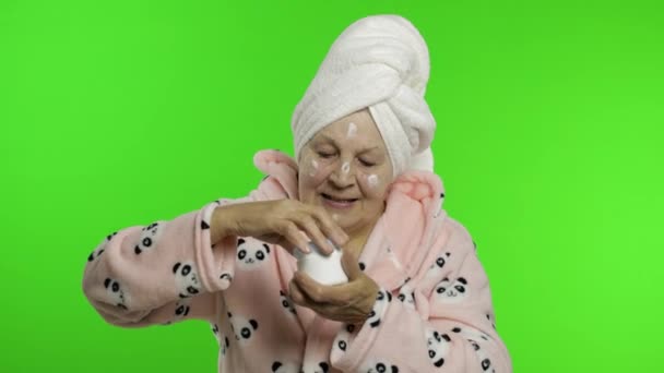 Ηλικιωμένη γιαγιά μετά το ντους. Γριά γυναίκα εφαρμογή ενυδατική κρέμα στο πρόσωπο - Πλάνα, βίντεο