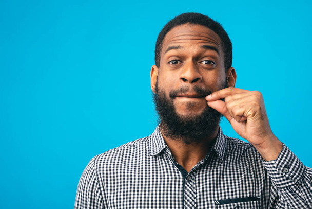 Funny black man making zipping lips gesture with hand - Photo, Image