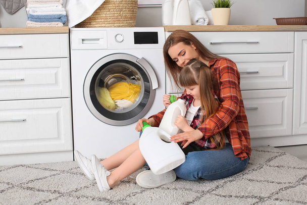 Kadın ve tatlı küçük kızı evde çamaşır yıkıyorlar. - Fotoğraf, Görsel