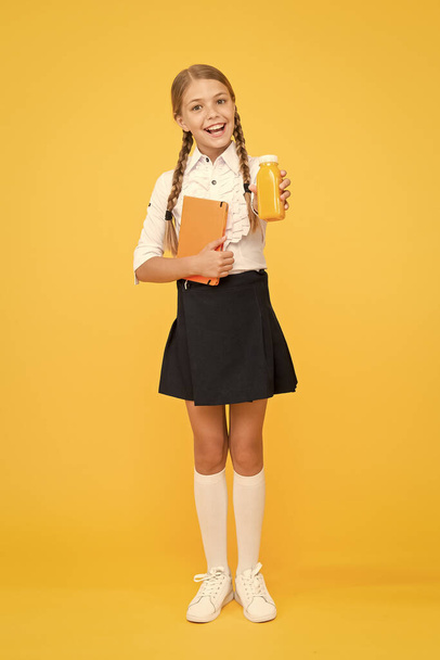This is my favorite taste. Healthy nutrition. Schoolgirl holding juice bottle on yellow background. Quenching thirst during school time. Healthy snack fruit smoothie. Smoothie detox. Yummy smoothie - Photo, Image