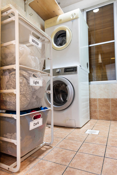Lavanderia per il lavaggio ordinati in gruppo di bianco, chiaro e scuro in cesto rack
 - Foto, immagini