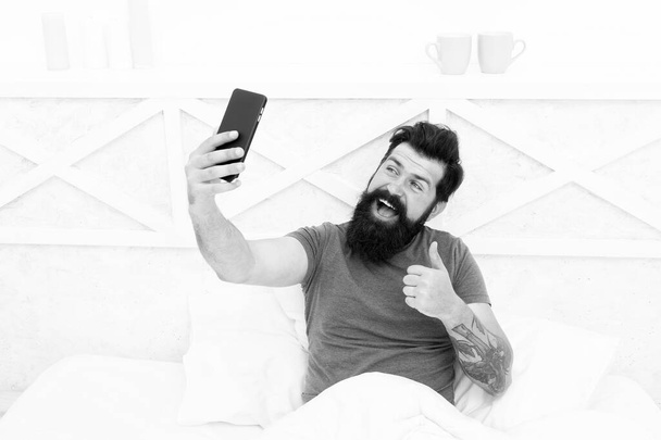 Just thumb up. Happy hipster give thumb up to phone camera. Bearded man smile with thumb up and smartphone. Gesturing satisfaction. Thumb up for new technology. Mobile lifestyle. Modern life - Zdjęcie, obraz