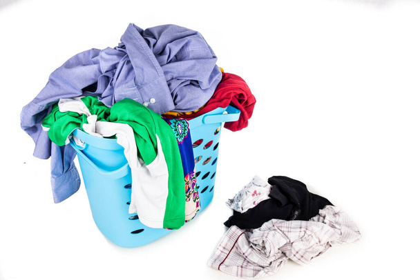 Wäschekorb voller Damen- und Herrenbekleidung zum Waschen vor weißem Hintergrund - Foto, Bild