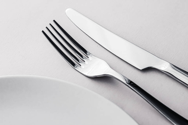 Κενό πιάτο και μαχαιροπήρουνα ως mockup που σε λευκό φόντο, κορυφαία επιτραπέζια σκεύη για διακόσμηση τραπέζι σεφ και το εμπορικό σήμα μενού - Φωτογραφία, εικόνα