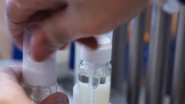 A gyár személyi védőfelszerelés gyártására szolgáló alkalmazottja egy kupakot pörget le egy fertőtlenítővel ellátott üvegről.. - Felvétel, videó