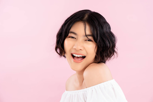 Улыбающаяся молодая милая азиатка с корейской короткой прической на мягком розовом фоне
 - Фото, изображение