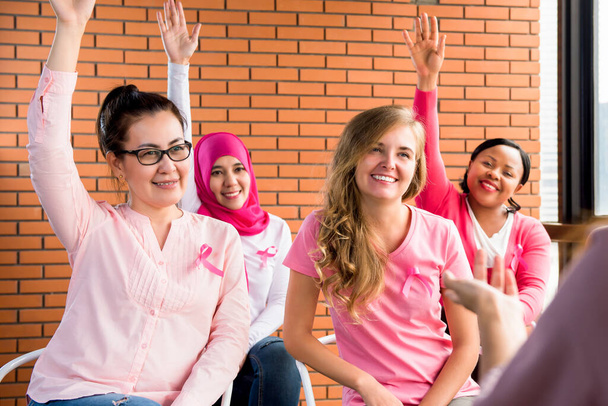 Meertalige vrouwen dragen roze kleurige kleren met linten vergadering voor borstkanker bewustmakingscampagne - Foto, afbeelding