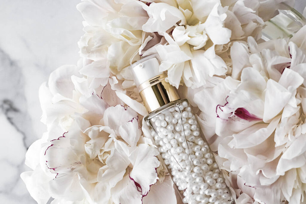Frasco cosmético luxuoso como produto antienvelhecimento de cuidados com a pele no fundo das flores, embalagem de etiqueta em branco para marcação de cuidados com o corpo
 - Foto, Imagem