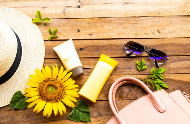 日焼け止めspf50化粧品ボディローションで皮膚の顔の健康管理、ピンクのハンドバッグサングラス、ライフスタイルの女性の帽子とライフスタイルの女性の黄色の花のひまわりは木の上で夏にリラックス - 写真・画像