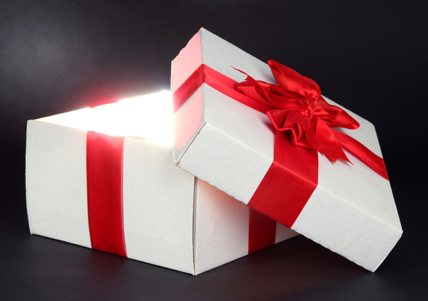 Gift box with bright light on it on dark grey background - Fotografie, Obrázek