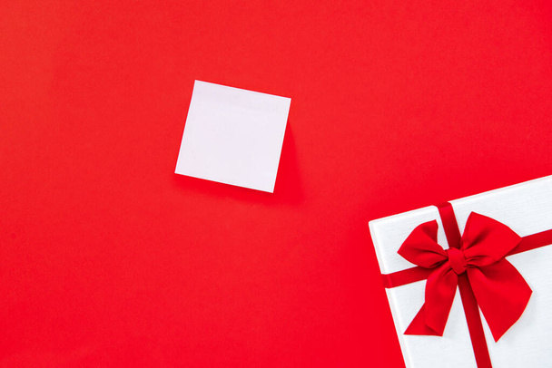 Tyhjä muistio punaisella taustalla lahjapaketti rajalla palkinto edustaa rakkautta ja romantiikkaa
 - Valokuva, kuva