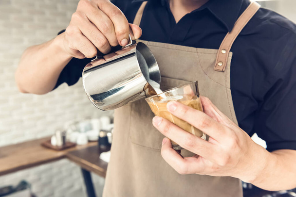 Επαγγελματίας barista ρίχνει ατμό γάλα σε φλιτζάνι καφέ κάνοντας τέχνη latte στο καφέ - Φωτογραφία, εικόνα