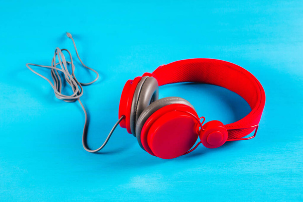 Piros fülhallgató kék háttérrel. Zenei koncepció - Fotó, kép