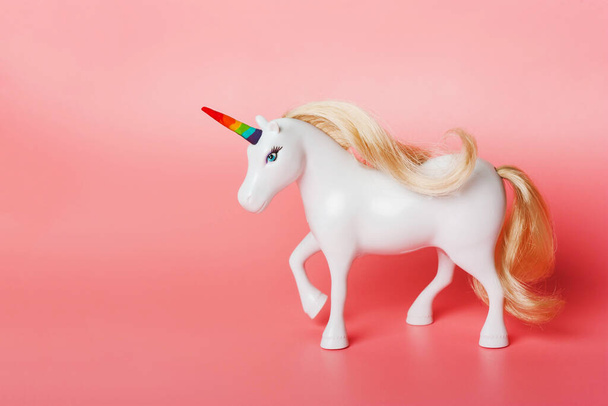 Unicornio con cuerno de colores arcoíris, bandera LGBT sobre fondo rosa
 - Foto, Imagen