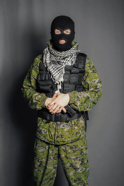 Een lid van de speciale politie, richt, houdt een pistool vast. Gekleed in een bivakmuts, camouflage uniform, kogelvrij vest. Speciale wapens en tactieken. Special Forces.SWAT. - Foto, afbeelding