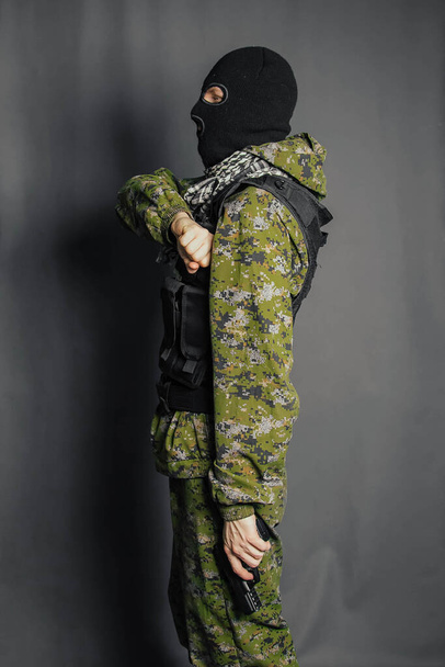 Ένα μέλος της ειδικής αστυνομικής ομάδας, σημαδεύει, κρατάει πιστόλι. Ντυμένος με κουκούλα, στολή καμουφλάζ, αλεξίσφαιρο γιλέκο. Ειδικά όπλα και τακτικές. Ειδικές Δυνάμεις: SWAT. - Φωτογραφία, εικόνα