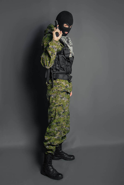 Un miembro del escuadrón especial de policía, apunta, sostiene una pistola. Vestido con pasamontañas, uniforme de camuflaje, chaleco antibalas. Armas y tácticas especiales. Fuerzas especiales.SWAT
. - Foto, Imagen