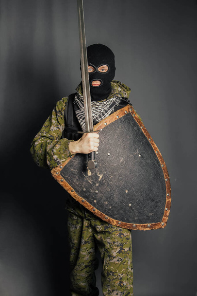 Modern warrior with medieval weapons in his hands. A soldier defends himself with a shield and attacks with a sword. Protection of law, law, order, property, money, peace of mind. - Photo, Image