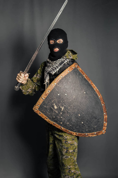 Modern warrior with medieval weapons in his hands. A soldier defends himself with a shield and attacks with a sword. Protection of law, law, order, property, money, peace of mind. - Fotografie, Obrázek