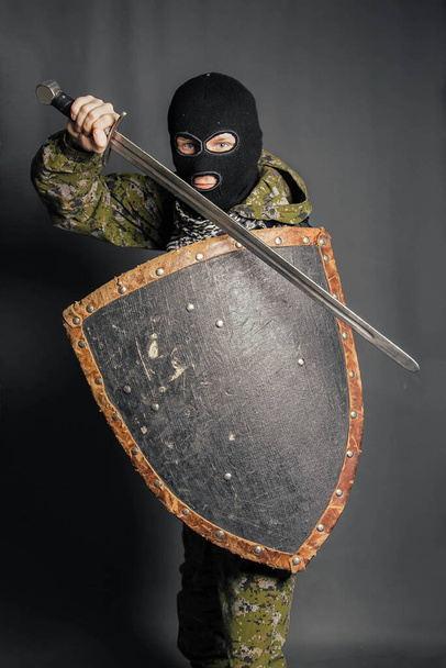 Moderní válečník se středověkými zbraněmi v rukou. Voják se brání štítem a útočí mečem. Ochrana práva, práva, pořádku, majetku, peněz, duševní pohody. - Fotografie, Obrázek