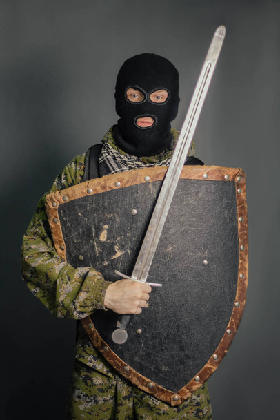 Modern warrior with medieval weapons in his hands. A soldier defends himself with a shield and attacks with a sword. Protection of law, law, order, property, money, peace of mind. - Photo, image