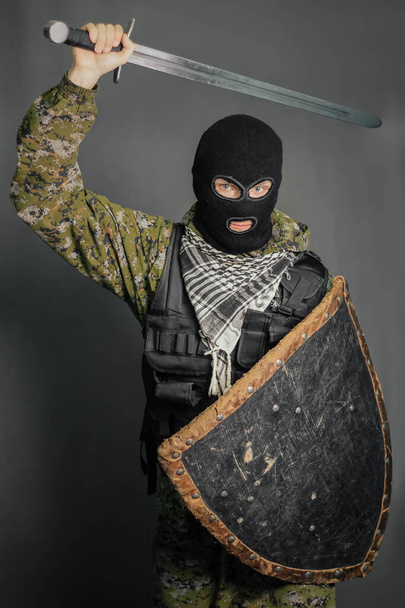 Modern warrior with medieval weapons in his hands. A soldier defends himself with a shield and attacks with a sword. Protection of law, law, order, property, money, peace of mind. - Фото, зображення