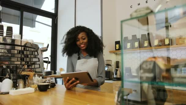 Happy young african woman with brown curly hair using the tablet in the coffee cafe. Portrait shot. - Video, Çekim
