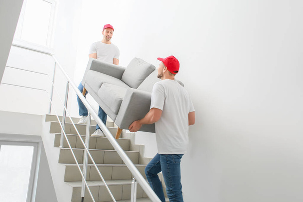 Loaders carrying furniture in the stairway - Foto, Imagen