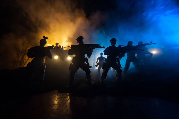 Έννοια πολέμου. Σκηνή μάχης στο φόντο του ουρανού ομίχλη πολέμου, Καταπολέμηση σιλουέτες κάτω από συννεφιά Skyline τη νύχτα. Στρατιωτικό όχημα με διακόσμηση έργων τέχνης στρατιωτών. Επιλεκτική εστίαση - Φωτογραφία, εικόνα
