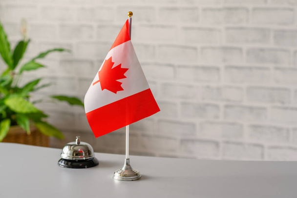 Silver vintage bell with national flag of Canada on reception desk with copy space. Hotel service. Travel, tourism. Concept. - Foto, Imagen