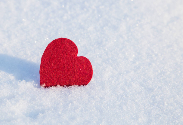 Coração de feltro vermelho no fundo branco da neve.Espaço de texto
. - Foto, Imagem
