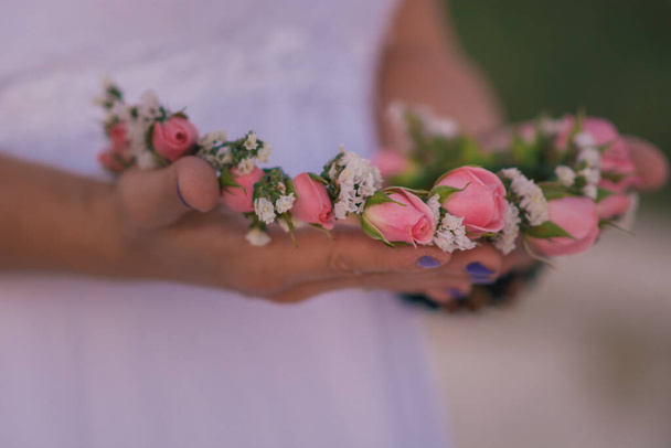 Les mains de la mariée avec une couronne de petites roses
. - Photo, image