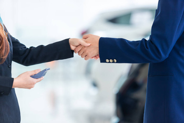Asian auto business, car sale, deal, gesture and people concept - close up of dealer new owner and shaking hands in auto showroom - Foto, imagen