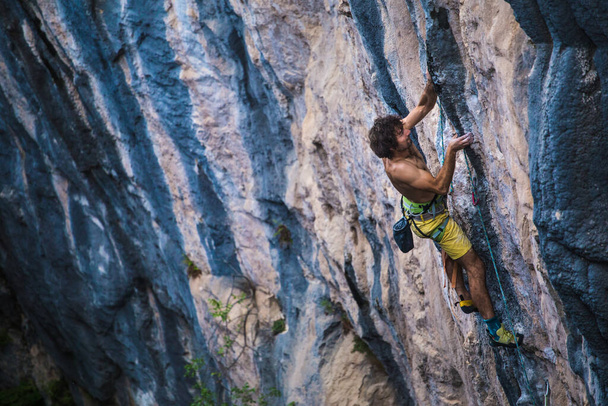 Um homem forte sobe uma rocha, músculos das costas fortes, escalada na Turquia, resistência e força de treinamento, homem em esporte extremo, escalador de rocha está treinando na natureza. - Foto, Imagem