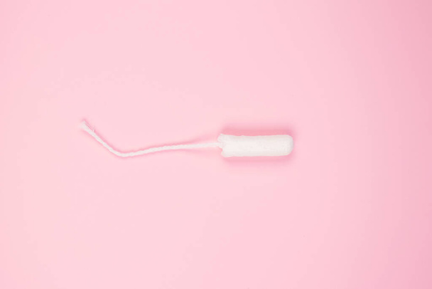 Clean cotton tampon on trendy pink background with copyspace for your text - critical days and menstruation concept. Flat lay minimalistic composition - for Menstrual Hygiene Day concept - 写真・画像